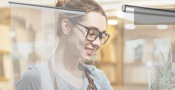 Frau neben einem Infektionsschutzrollo