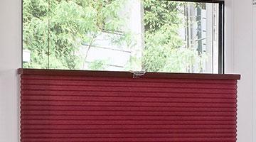 Rotes Basis Wabenplissees am weißen Fenster